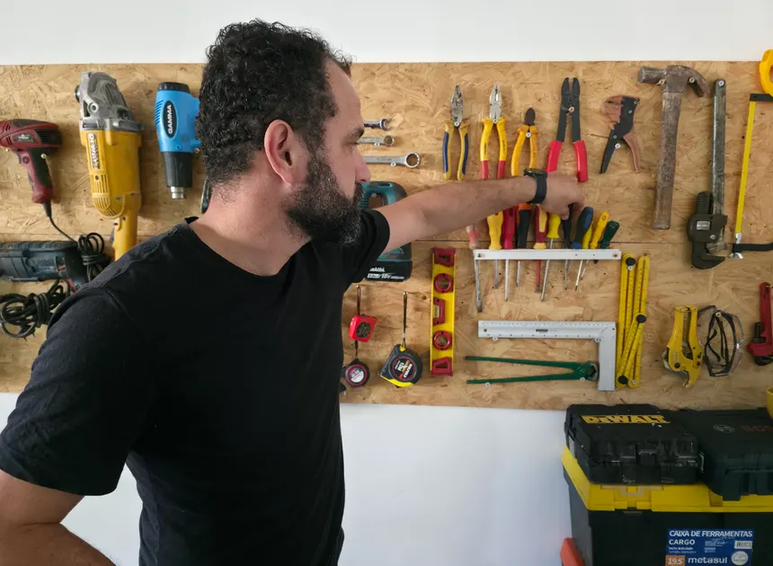 Instrutor selecionando ferramentas na bancada da oficina